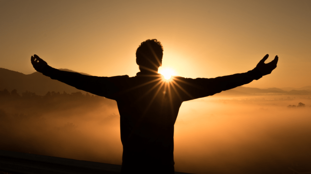 A spiritual man facing the sun with arms wide open